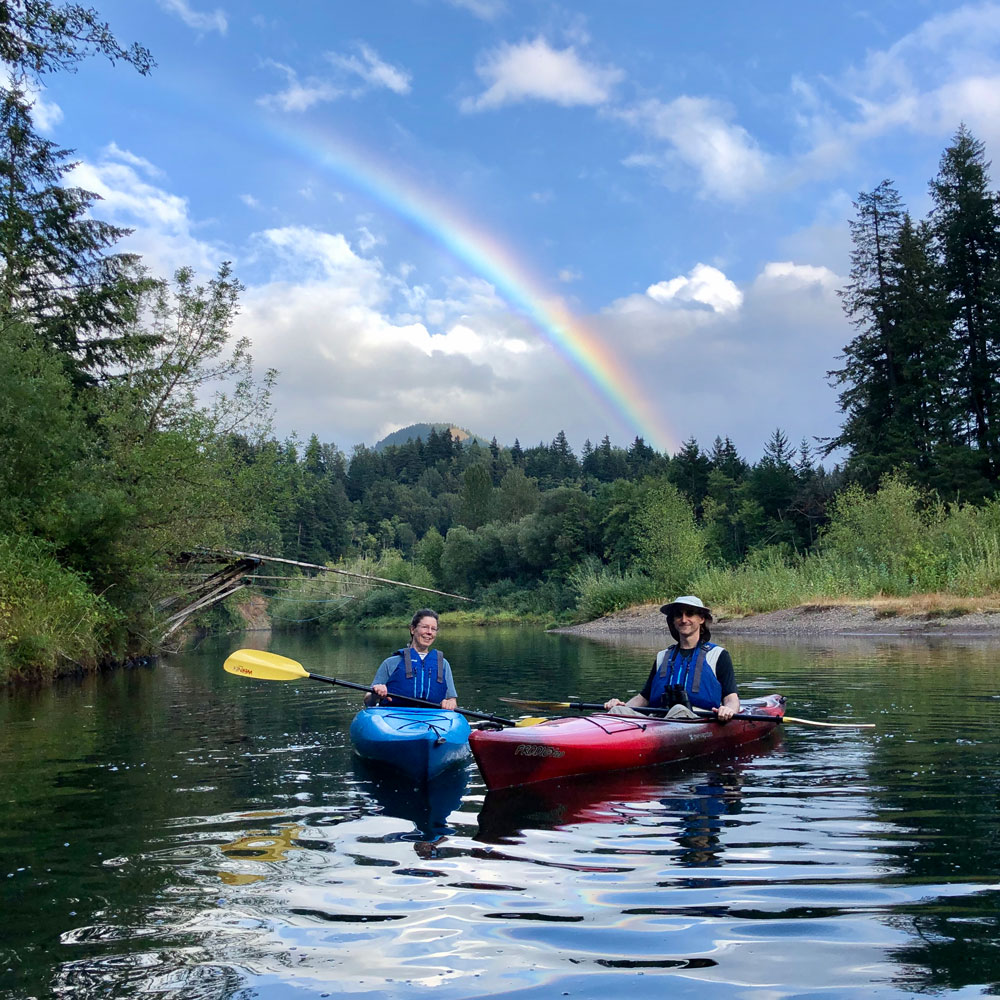 Two paddlers under a rainbow